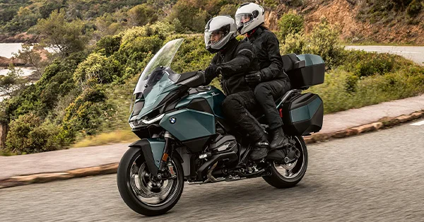 2026 BMW R 1300 RT touring bike with rider and passenger on a scenic road trip.