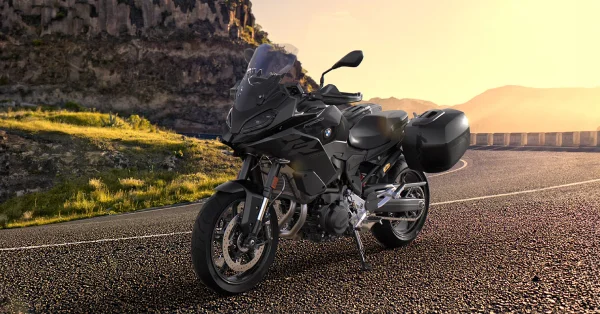2026 BMW F 900 XR sport-touring motorcycle riding along a cliffside road at sunset.